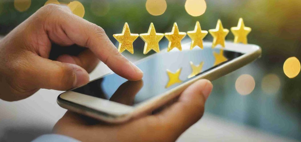 close up on customer man hand pressing on smartphone screen with gold five star rating feedback icon and press level three rank (good) for give score point to review the service business concept