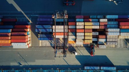Shipping containers in terminal, Unloading containers in warehouse on railroad platform with cranes and forklifts, aerial view